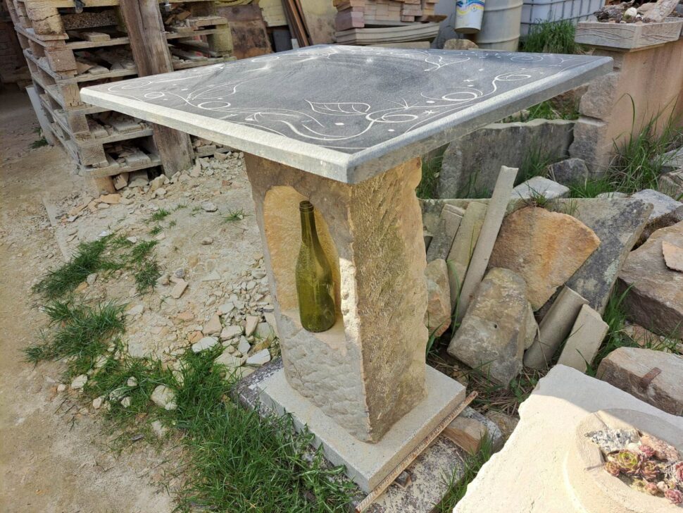 Stůl a nikou, který má nohu vytvořenou z přírodního pískovce a deska stolu je z mramoru s kresbou.