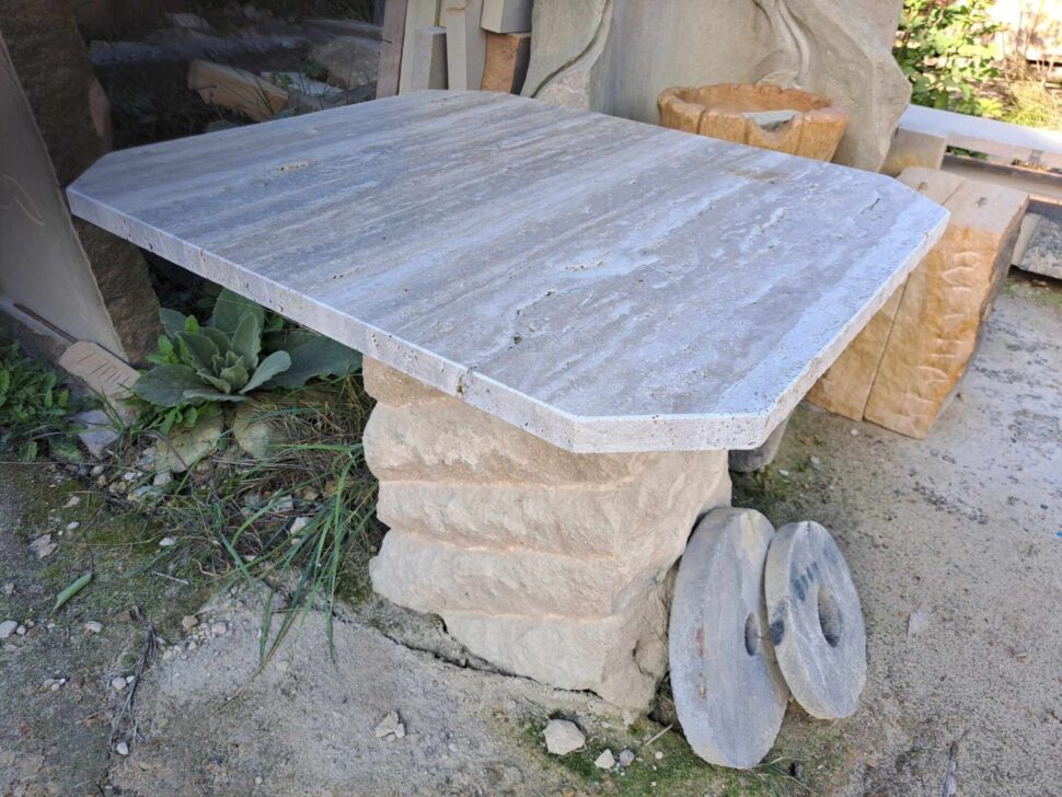 Nízký stůl, který má jednu masivní pískovcovou nohu a na ni stolovou travertinovou desku.