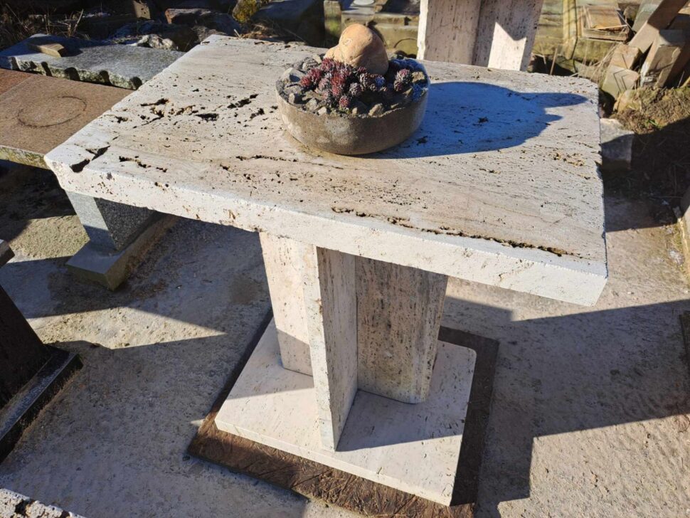 Stůl z travertinu složený z jedné atypicky tvarované nohy s podstavcem a stolové desky.