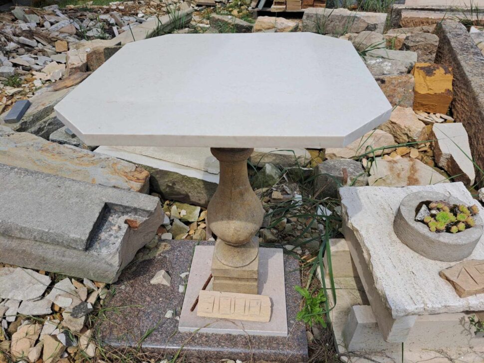Stůl z balustry z umělého pískovce a stolové desky z bílého umělého kamene o osmi hranách.