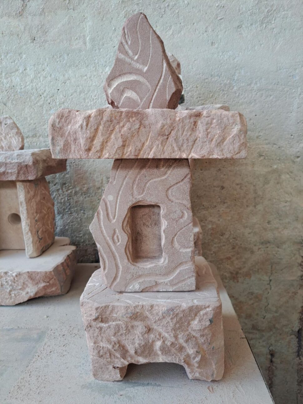 Lucerna z přírodního pískovce, která je částečně broušená a částečně přírodně opracovaná. Lucerna je vytvořená ze čtyř částí a stojí na podstavci s nožičkami.