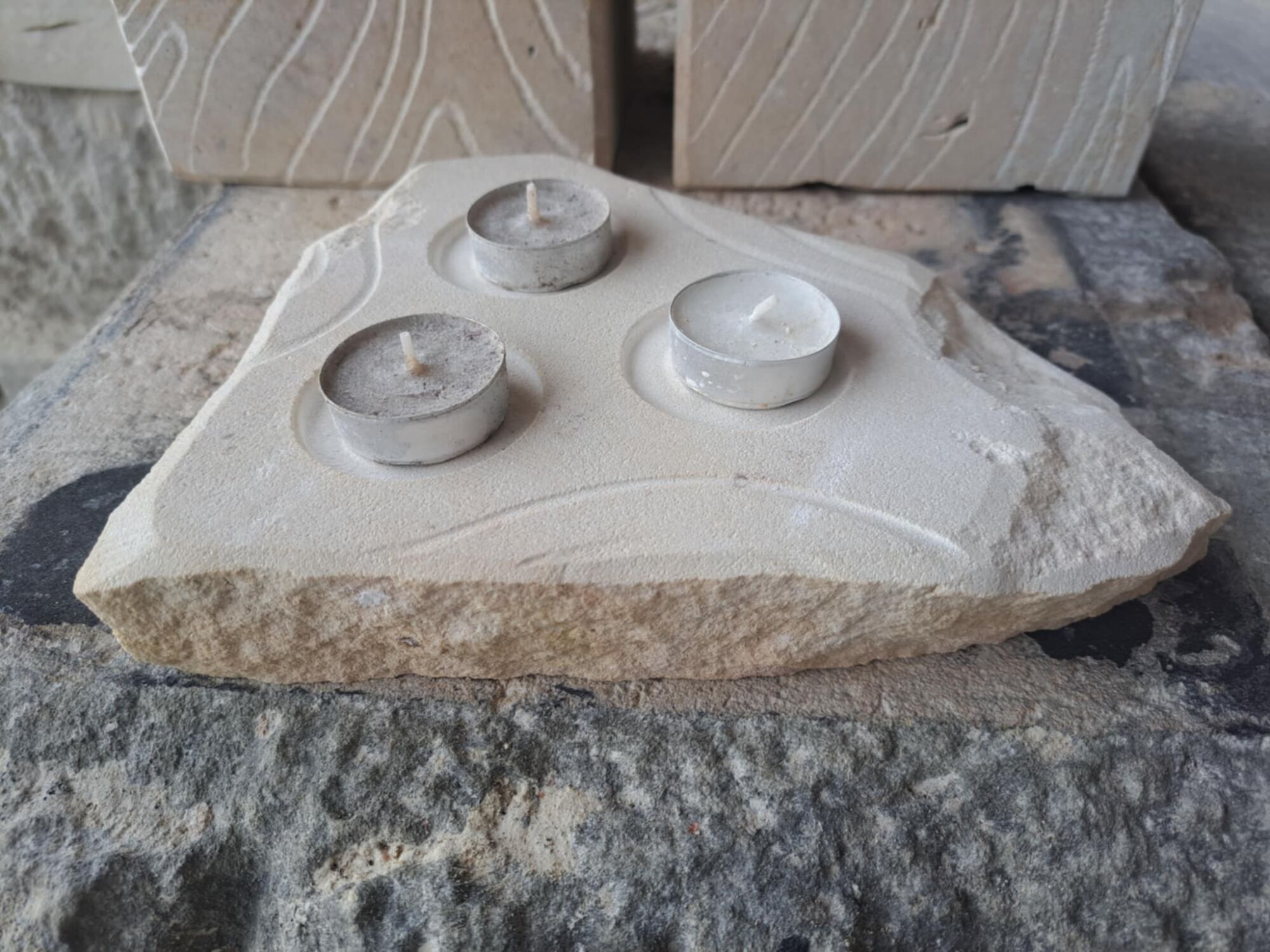 Atypicky tvarovaný svícen z přírodního pískovce na tři čajové svíčky.