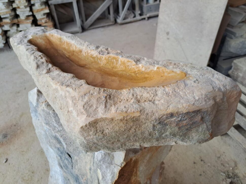 Přírodně opracované pítko z&nbsp;hořického žlutého pískovce. Pítko má podlouhlý nepravidelný tvar. Připomínající zahnutý trojúhelník.