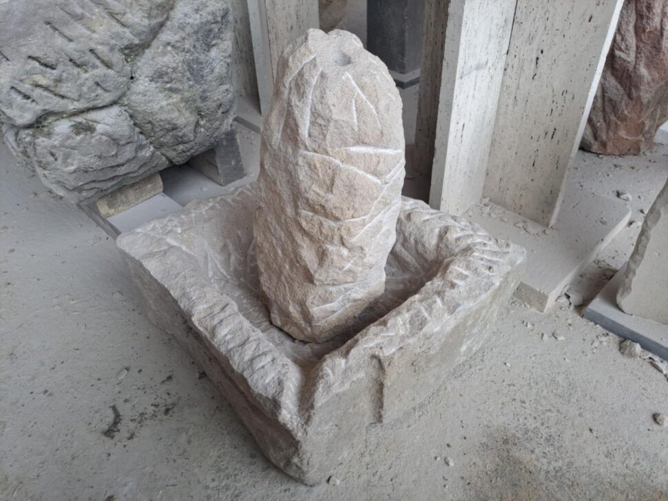 Fontána z&nbsp;přírodního pískovce. Fontána je vytvořená ze dvou kusů. Nádržky ve tvaru čtverce s&nbsp;odtokem pro zadržení vody a&nbsp;pískovcového sloupu. Skrz fontánu je vyvrtaný otvor pro vodu, která vyvěrá na&nbsp;vrcholu sloupu a&nbsp;volně stéká do&nbsp;nádržky.