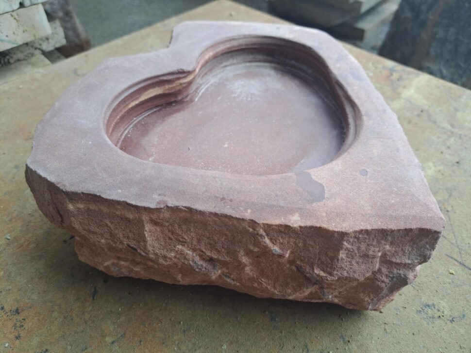 Pítko z&nbsp;červeného trutnovského přírodního pískovce. Boky pítka jsou štípané a&nbsp;vrch broušený do&nbsp;tvaru srdce.